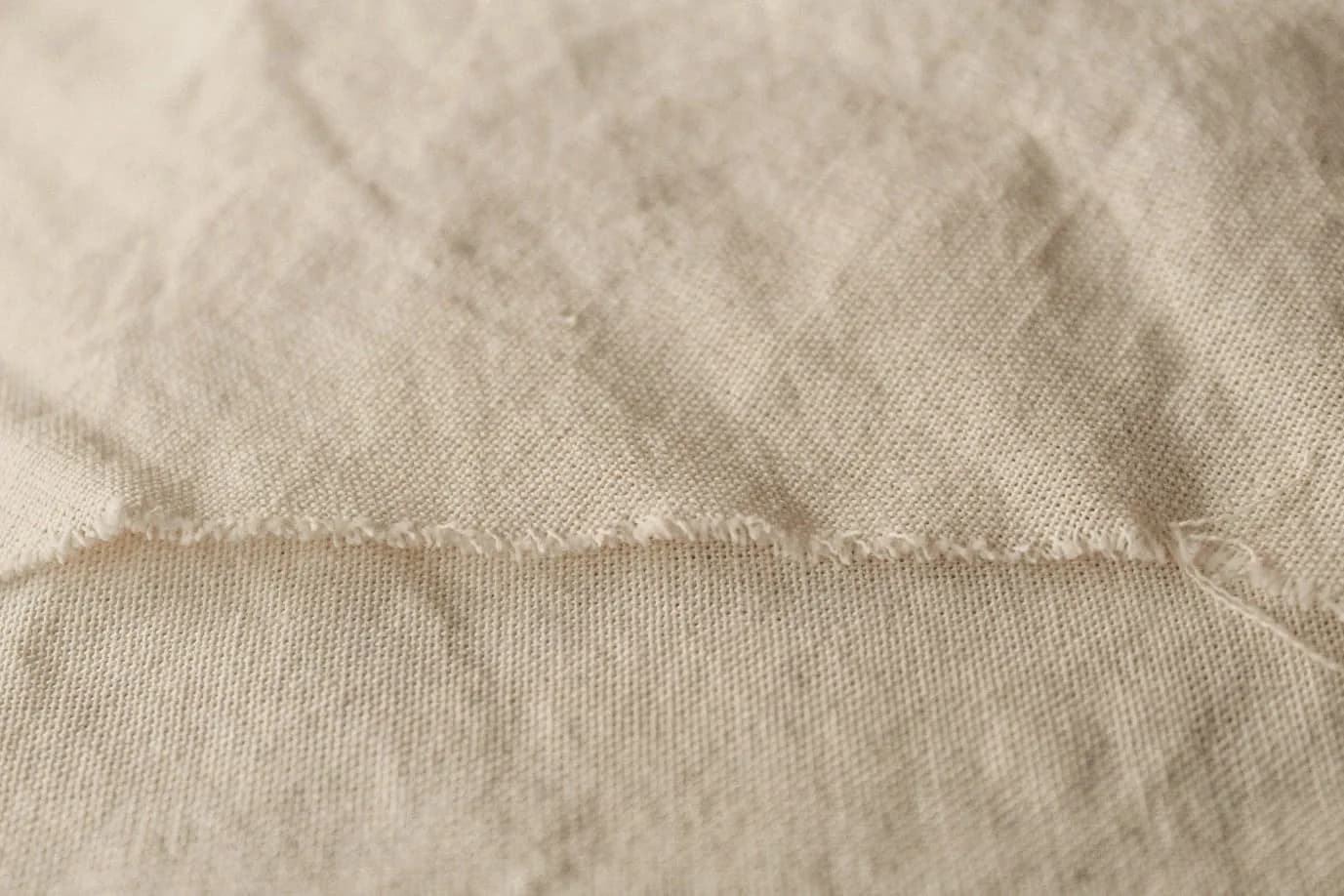 Close-up of undyed handwoven cloth, its weave and frayed edge in sharp detail